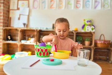 Beautiful blond toddler girl playing  meals using plastic food at kindergarten