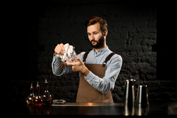 Bartender standing on the bar counter rubs the glass cup with a rag