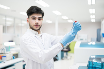 Portrait scientist man holding test tube and standing with automatic machine in laboratory.Researcher analysis blood chemistry in medical laboratory. Medical healthcare technology research concept.