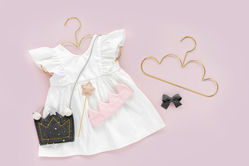 White dress with kids handbag shape of crown on golden hanger . Set of  baby clothes and...