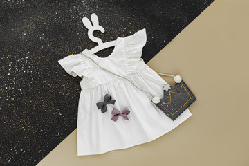 White dress with kids handbag shape of crown on cute hanger with bunny ears. Set of  baby clothes...
