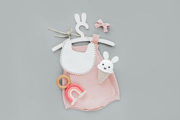 Pink knitted bodysuit on cute hanger with bunny ears with bib, toy ice cream and sunglasses. Set of...