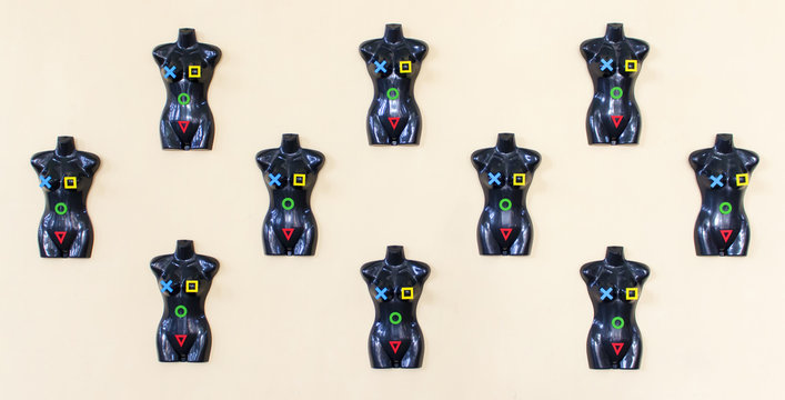 A set of torso of black plastic mannequins with colored signs hanging on the wall - Powered by Adobe