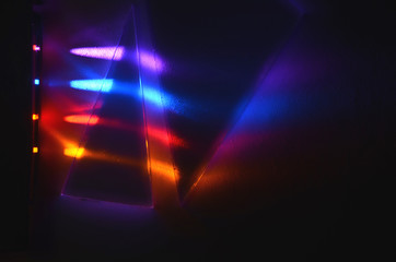 Fototapeta na wymiar Four different light beams are refracted in two triangular prisms, first a 30 degrees refract the beams downwards, then a 45 degrees prism refract even more the other way, seen on a dark background.