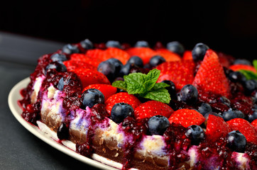 Fresh strawberries, blueberries and cherry jam cake. Dark background. Low depth of field