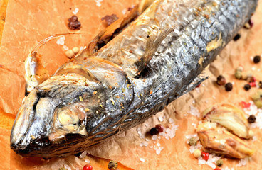Detail of of baked mackerel with garlic, pepper and coarse salt on baking paper.