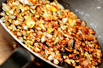 Detail of golden chopped onion fried in oil in pan. Close-up