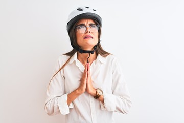 Beautiful businesswoman wearing glasses and bike helmet over isolated white background begging and praying with hands together with hope expression on face very emotional and worried. Asking