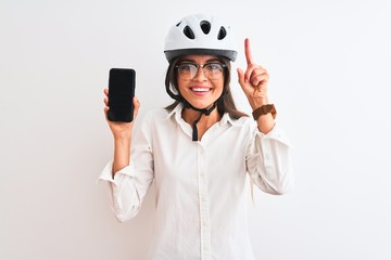 Young businesswoman wearing bike helmet holding smartphone over isolated white background surprised with an idea or question pointing finger with happy face, number one