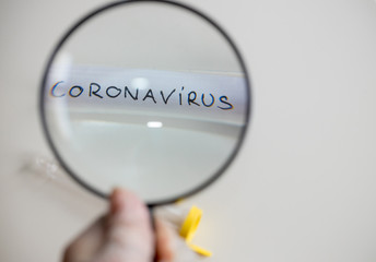 Coronovirus vial under a magnifying glass, The concept of research and finding a cure for a dangerous virus