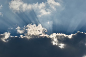 Fototapeta na wymiar Rays of sun passing through the dark clouds with blue sky background
