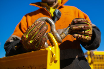 Rigger high risk worker wearing safety heavy duty glove, inserting pin into D- shape shackle which...