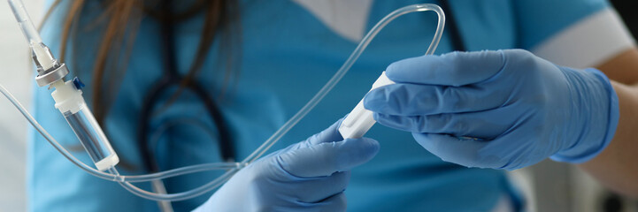 Female nurse hand in blue protective gloves hold dropper against medicine hospital background....