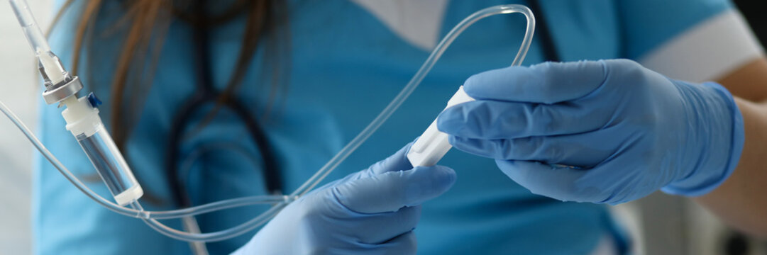 Female nurse hand in blue protective gloves hold dropper against medicine hospital background. Medical education concept