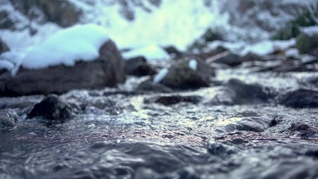 Nature background with snowy mountains and river among rocks and stones