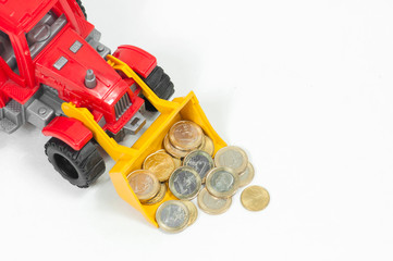 coins of twenty fifty cents and one Euro in the bucket of a toy red bulldozer on the left side of...