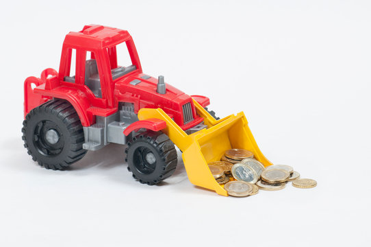 coins of twenty fifty cents and one Euro in the bucket of a toy red bulldozer on the left side of the image on a white background side view from the front