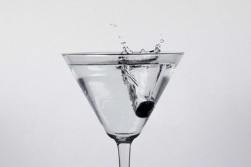Blueberry splashing water in a cocktail glass on a white background
