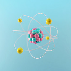 3D rendered illustration of elementary particles in atom on blue background. Physics concept