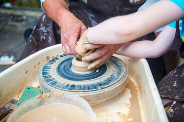 The potter makes pottery dishes on potter's wheel.