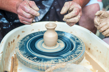 The potter makes pottery dishes on potter's wheel.
