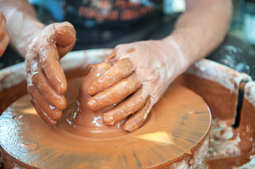 The potter makes pottery dishes on potter's wheel.