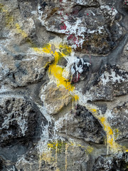 wall of large multicoloured stones with large streaks of paint and cement around it