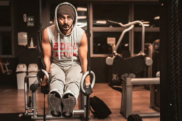 Sporty man with a beard is doing exercise on a horizontal bar to strengthen the abdominal muscles....