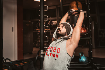 Sporty man with a beard is doing exercise on a horizontal bar to strengthen the abdominal muscles....