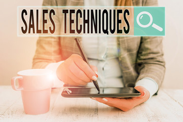 Conceptual hand writing showing Sales Techniques. Concept meaning methods that sales professionals use to create revenue Business woman sitting with mobile phone and cup of coffee