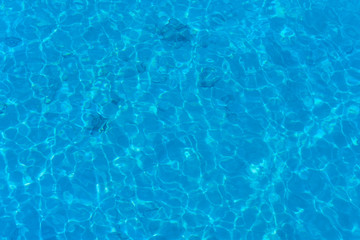 Background of water in blue swimming pool, water surface with a sun reflection