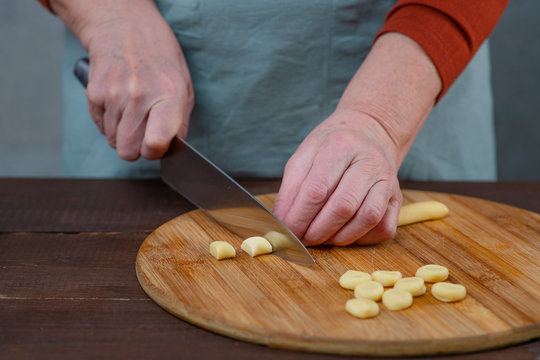 Woman cook sculpts dumplings with his hands, close-up. On the table is minced meat and rolled circles of dough