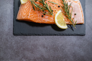 Fresh fish. Raw salmon on slate plate with rosemary and lemon. Copy space.