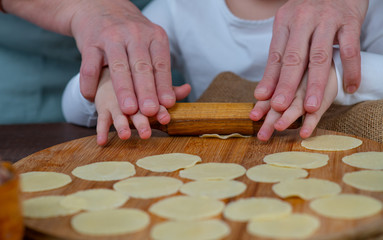 Woman cook sculpts dumplings with his hands, close-up. On the table is minced meat and rolled...