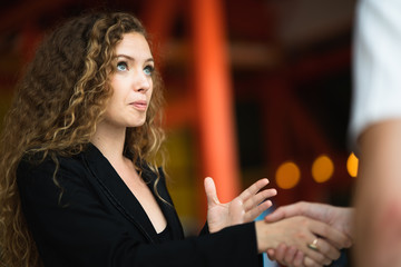 Shot of business woman greeting with the man in front of her in first meet and shake hand in meeting room atmosphere , Concept success business discussion, Selective focus on business woman.