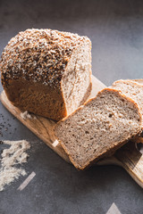Loaf and slices of homemade buckwheat bread on wooden table.
