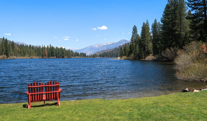 Landscape of red chair by Hume Lake with view of forest and mountains at Kings Canyon National Park in California