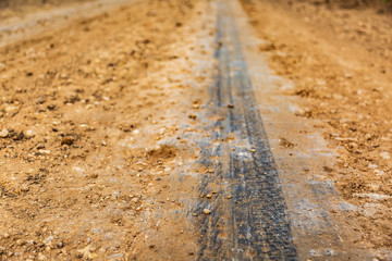a tread track left on a dirt road with a starting car on a hot summer day