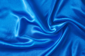 Blue silk background with a folds.  Abstract texture of rippled satin surface