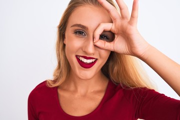 Young beautiful woman wearing red t-shirt standing over isolated white background with happy face smiling doing ok sign with hand on eye looking through fingers