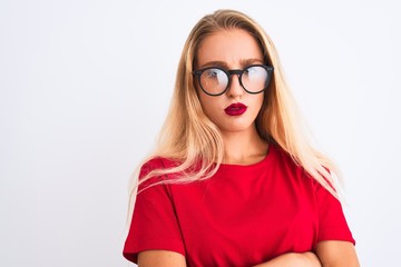 Young beautiful woman wearing red t-shirt and glasses standing over isolated white background skeptic and nervous, disapproving expression on face with crossed arms. Negative person.