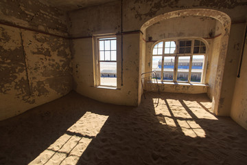 Abandoned and forgotten building and room left by people and being taken over by encroaching sandstorm, Kolmanskop ghost town, Namib Desert