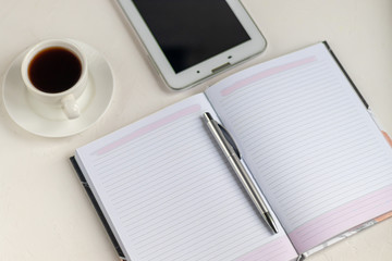 White office desk with necessary items on it. Diary with pen, Samsung phone. White cup of coffee. Top view with copy space,