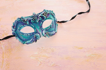 Photo of elegant and delicate blue Venetian mask over pastel wooden background