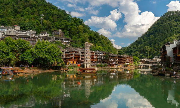 Sunset on the shore of the Tuojiang River. Colorful views of the green river, the chinese old town houses and the Wanmingta Pagoda in Fenghuang Ancient Town, Hunan province, China