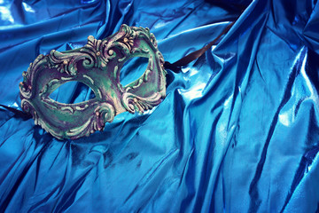 Photo of elegant and delicate Venetian mask over blue silk background