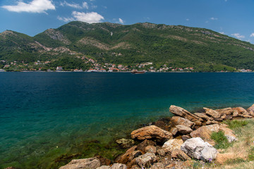 Fototapeta na wymiar Bay of Kotor, also known as Kotorska Boka, during a quiet summer afternoon with mountains reflecting in the waters of the Adriatic sea.