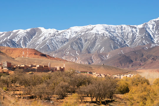 White mountains beyond a berberic town at the Atlas Mountains in Morocco