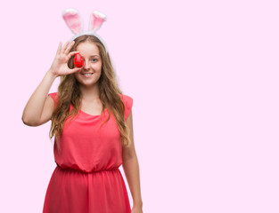 Obraz na płótnie Canvas Young blonde woman wearing easter bunny ears with a happy face standing and smiling with a confident smile showing teeth