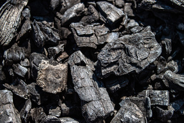 Ash of a burned-out fire. Background of burnt firewood.  Background with black burnt wood. Charcoal texture backdrop. Bonfire covered with ashes and sawdust closeup